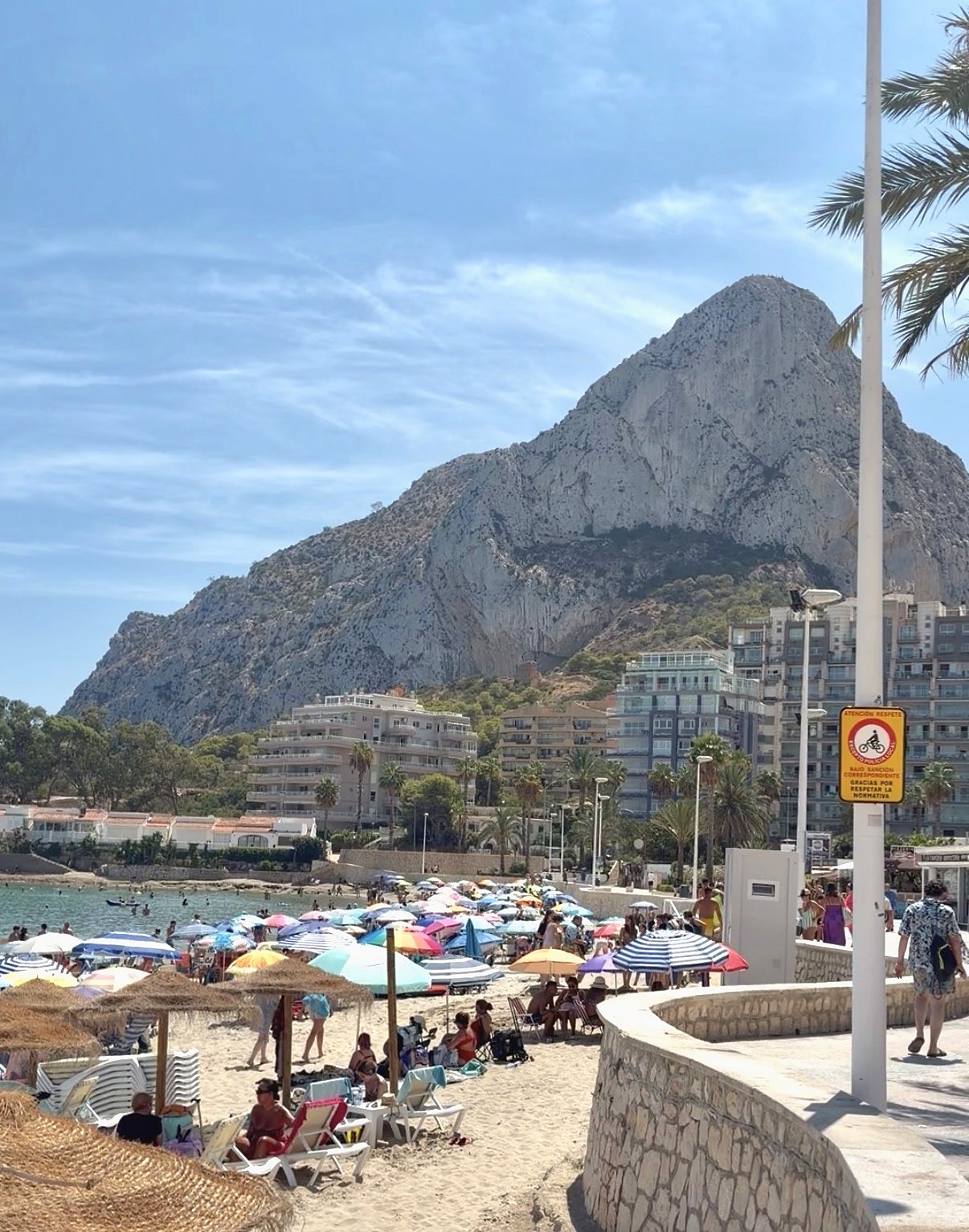 Playa de la Fossa v Calpe so slnečníkmi a promenádou pod masívom Peñónu de Ifach
